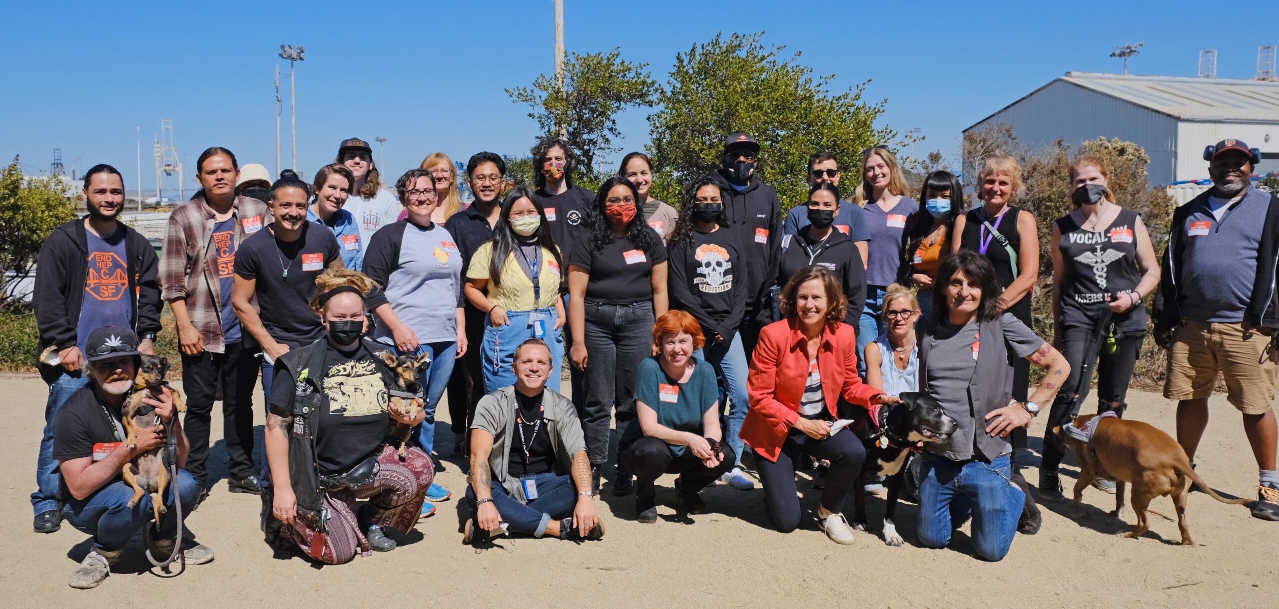 A group of people pose together with a backdrop of blue skies and trees